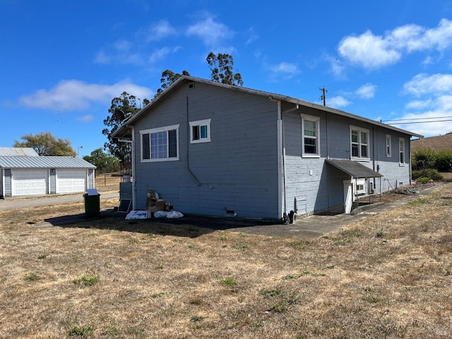 rear view of house with a lawn, an outdoor structure, and a garage