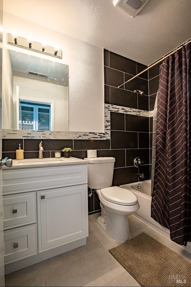 full bathroom featuring shower / bath combination with curtain, vanity, a textured ceiling, tile patterned floors, and toilet