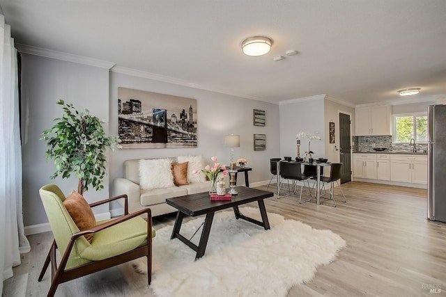 living room with crown molding, sink, and light hardwood / wood-style flooring