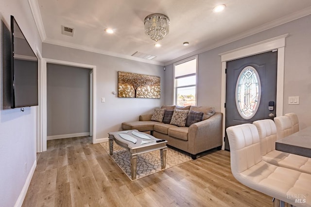 living room with a notable chandelier, light hardwood / wood-style flooring, and crown molding