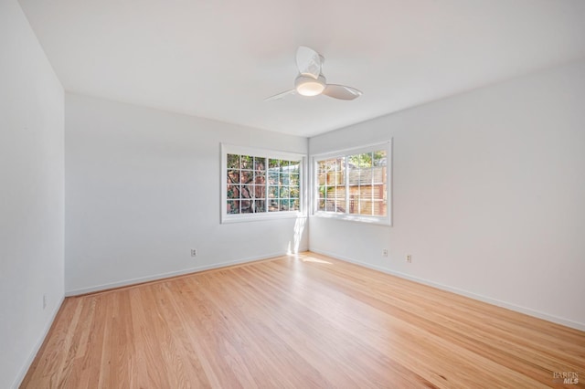 unfurnished room with a ceiling fan, baseboards, and light wood-style floors