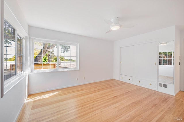 empty room with baseboards, ceiling fan, visible vents, and light wood finished floors