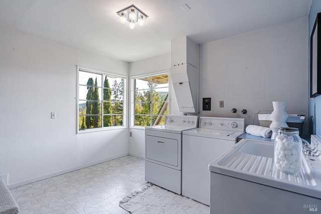 laundry room featuring independent washer and dryer, laundry area, a sink, and baseboards