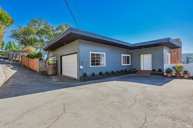 single story home featuring driveway, a chimney, fence, and a garage