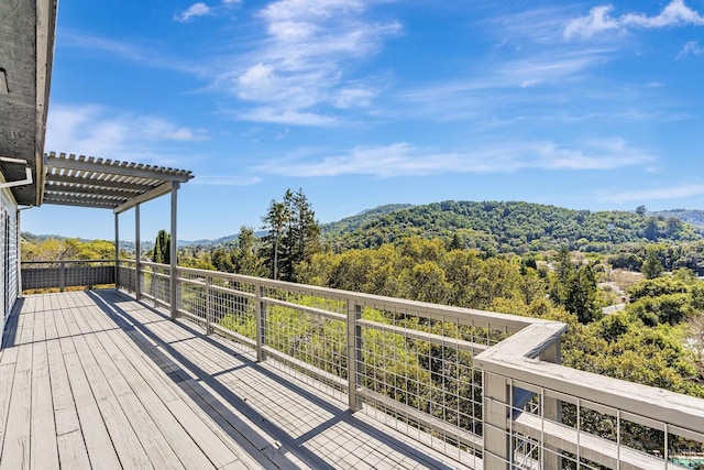 deck with a wooded view and a pergola