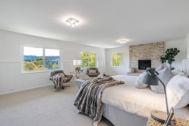 carpeted bedroom featuring a wainscoted wall and a fireplace