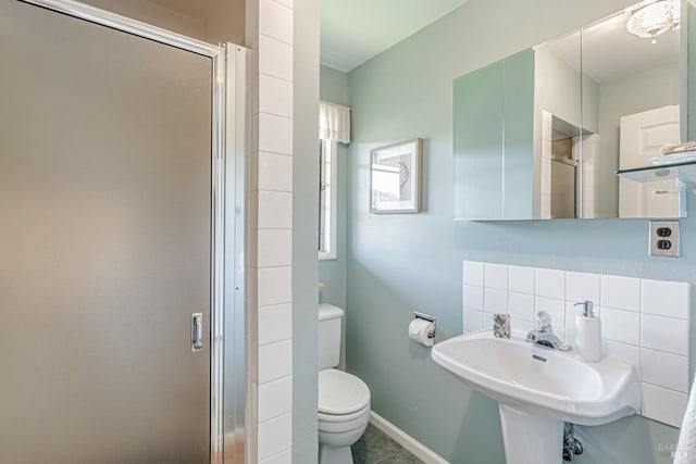bathroom featuring toilet, a sink, a shower stall, baseboards, and decorative backsplash