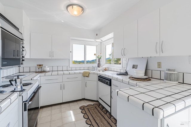 kitchen with washer / dryer, white cabinets, white appliances, tile countertops, and light tile patterned floors