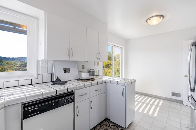 kitchen with white cabinets, white dishwasher, tile countertops, and visible vents