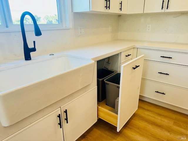 kitchen featuring wood-type flooring, sink, and white cabinets