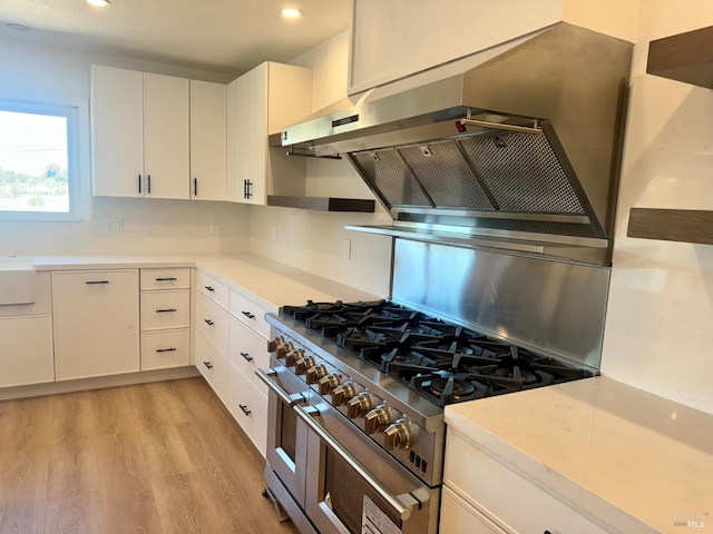 kitchen with range with two ovens, light hardwood / wood-style flooring, and white cabinetry