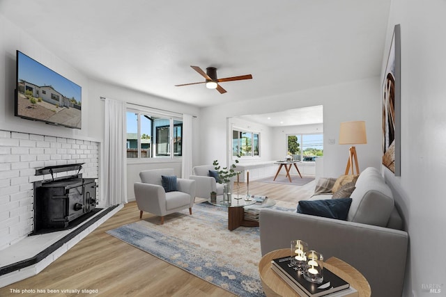 living room featuring a wood stove, wood-type flooring, ceiling fan, and a fireplace