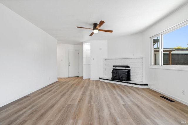 unfurnished living room with ceiling fan, light wood-type flooring, and a brick fireplace