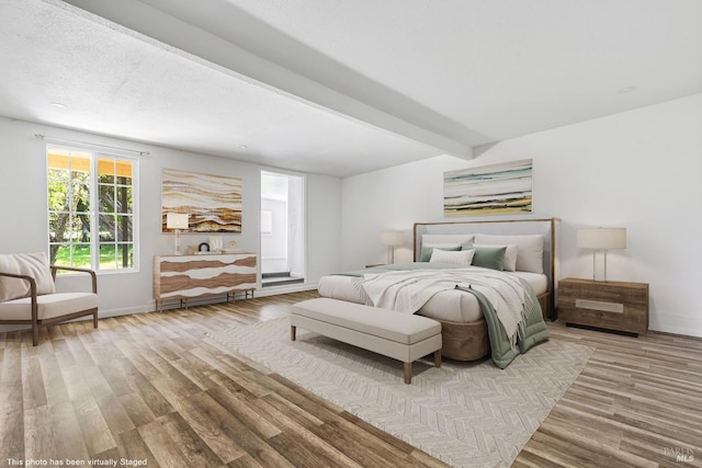 bedroom featuring wood-type flooring and beamed ceiling