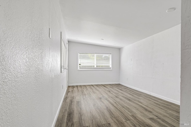 spare room with lofted ceiling and hardwood / wood-style floors