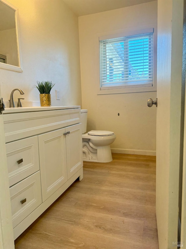 bathroom with wood-type flooring, vanity, and toilet