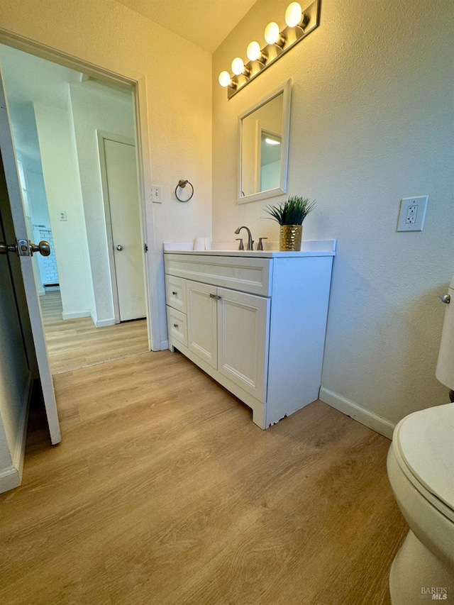 bathroom featuring wood-type flooring, vanity, and toilet