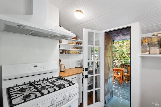 kitchen featuring white range with gas cooktop, vaulted ceiling, extractor fan, and wooden counters