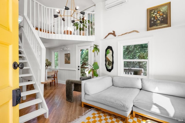 living room with dark hardwood / wood-style flooring, a chandelier, a wall unit AC, and a wealth of natural light