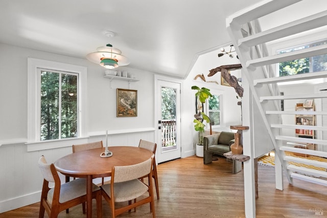 dining space with wood walls and light hardwood / wood-style floors