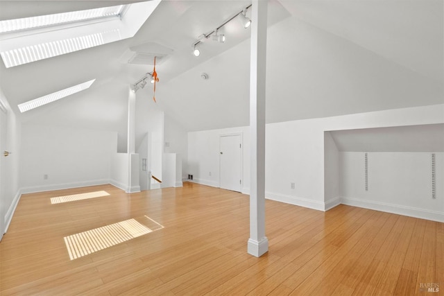 bonus room with lofted ceiling with skylight and light hardwood / wood-style flooring