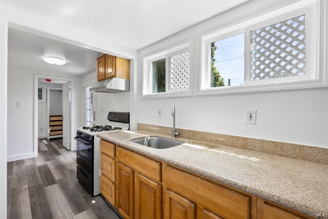 kitchen featuring light stone countertops, dark wood-type flooring, gas range gas stove, and sink