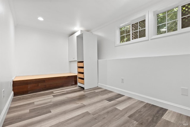 basement with crown molding and light hardwood / wood-style flooring