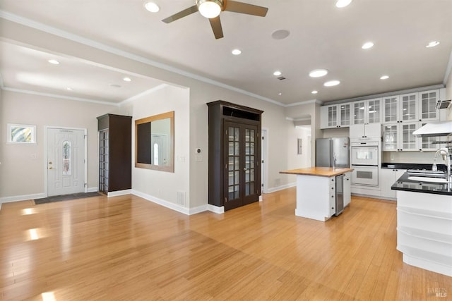 kitchen with white cabinets, stainless steel refrigerator, light wood-type flooring, and wood counters