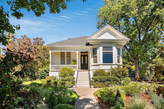 bungalow-style house featuring covered porch, a shingled roof, and stairway