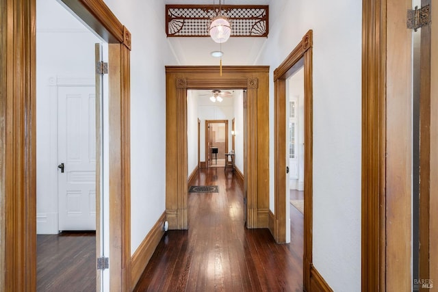 corridor with baseboards and dark wood-type flooring