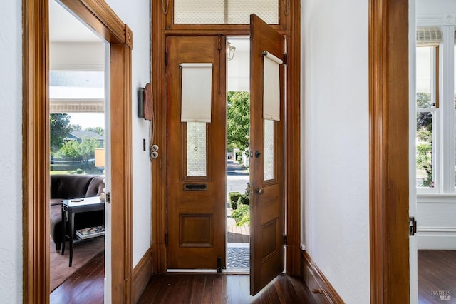 doorway to outside featuring baseboards and dark wood finished floors