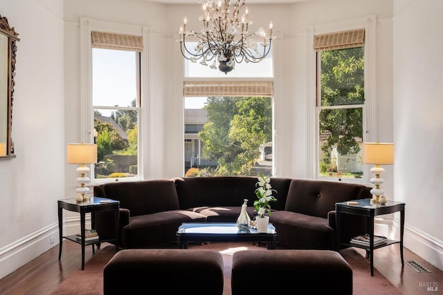 interior space featuring baseboards, a chandelier, wood finished floors, and visible vents