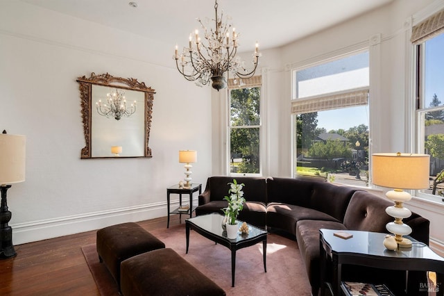 living area with plenty of natural light, baseboards, wood finished floors, and a notable chandelier