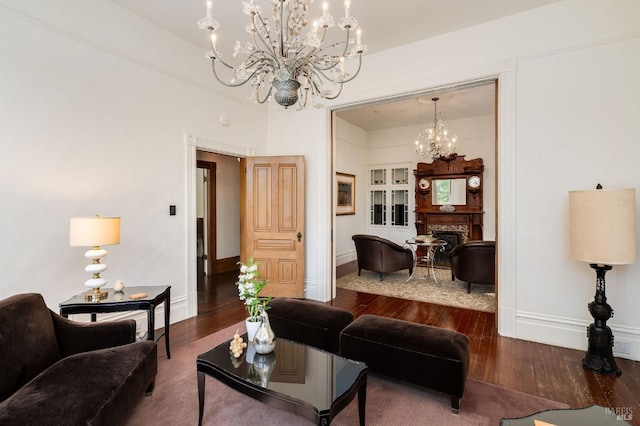 living room with baseboards, a chandelier, wood finished floors, and a fireplace