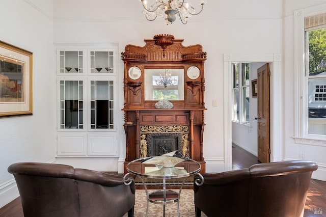 living area with dark wood-style flooring, baseboards, an inviting chandelier, and a large fireplace