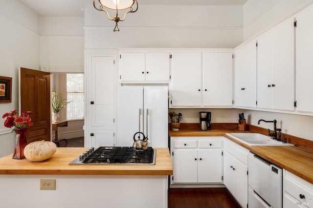 kitchen with white appliances, white cabinetry, butcher block countertops, and a sink