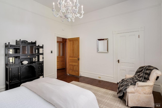 bedroom with baseboards, wood finished floors, and a notable chandelier