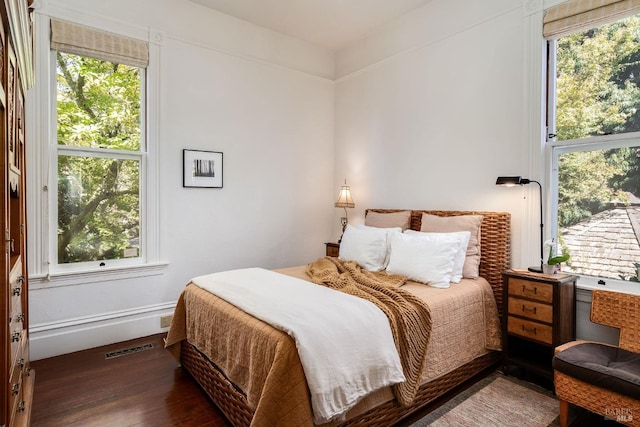 bedroom with multiple windows and dark hardwood / wood-style floors