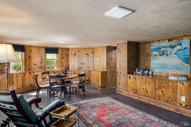 dining room with wood walls and a textured ceiling