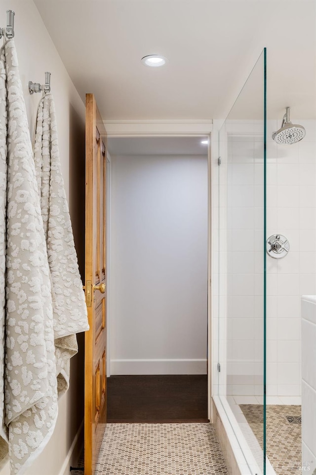 full bathroom with recessed lighting, baseboards, wood finished floors, and a tile shower
