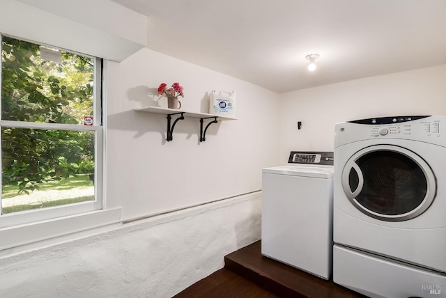 washroom featuring a wealth of natural light, laundry area, dark wood-type flooring, and washing machine and clothes dryer