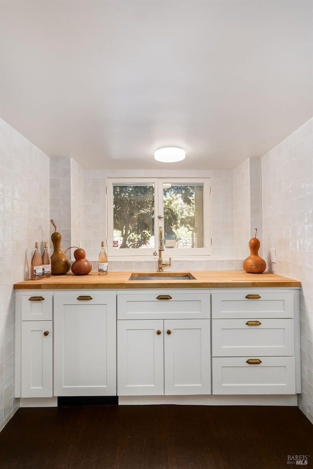 interior space with tile walls, butcher block countertops, and a sink