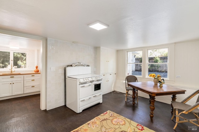 interior space with white stove, white cabinetry, and plenty of natural light