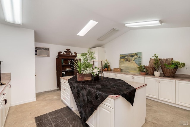 kitchen with white cabinets, an AC wall unit, light colored carpet, and vaulted ceiling