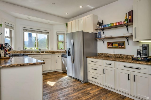 kitchen featuring stainless steel appliances, dark hardwood / wood-style flooring, dark stone counters, and white cabinetry