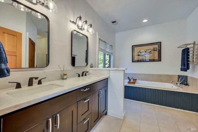 bathroom featuring tiled tub, tile patterned floors, and vanity