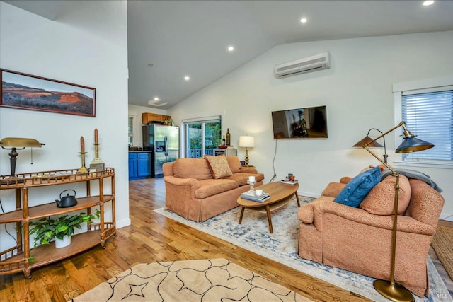 living room with plenty of natural light, light hardwood / wood-style floors, a wall mounted AC, and high vaulted ceiling