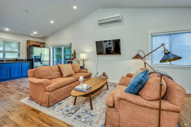 living room with an AC wall unit, high vaulted ceiling, and light hardwood / wood-style flooring