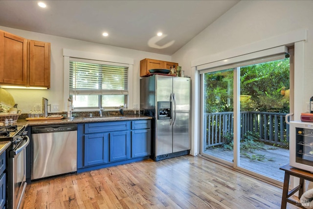 kitchen with light hardwood / wood-style floors, appliances with stainless steel finishes, sink, and vaulted ceiling