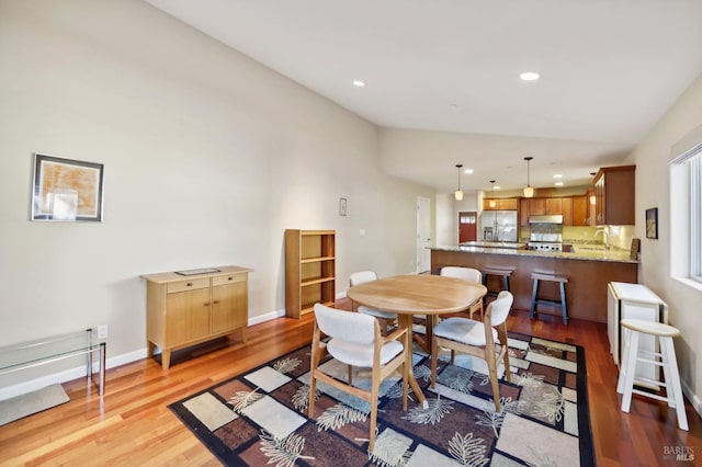 dining space featuring light hardwood / wood-style flooring, lofted ceiling, and sink